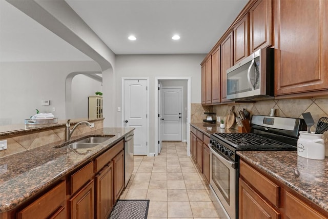 1017 Sussex Way, Round Rock, TX 78665 - kitchen with stainless steel appliances, a sink, arched walkways, decorative backsplash, and brown cabinetry