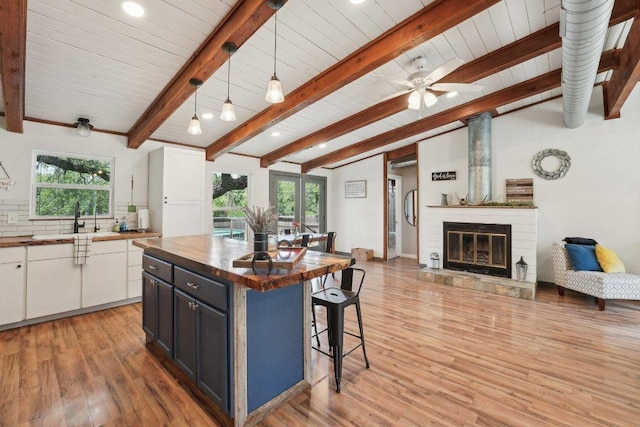 360 Little Barton Dr, Dripping Springs, TX 78620 - kitchen with butcher block countertops, a sink, a breakfast bar area, light wood-type flooring, and open floor plan