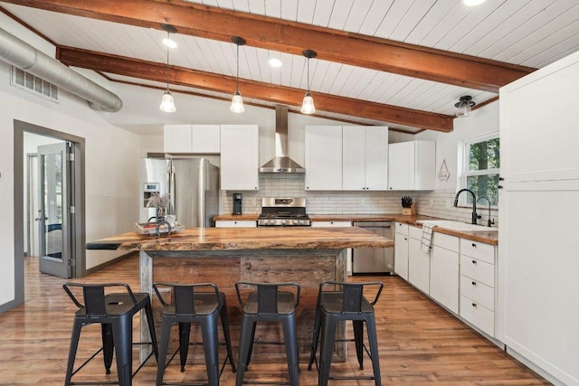 360 Little Barton Dr, Dripping Springs, TX 78620 - kitchen featuring appliances with stainless steel finishes, wall chimney range hood, a sink, a kitchen breakfast bar, and wooden ceiling with exposed beams