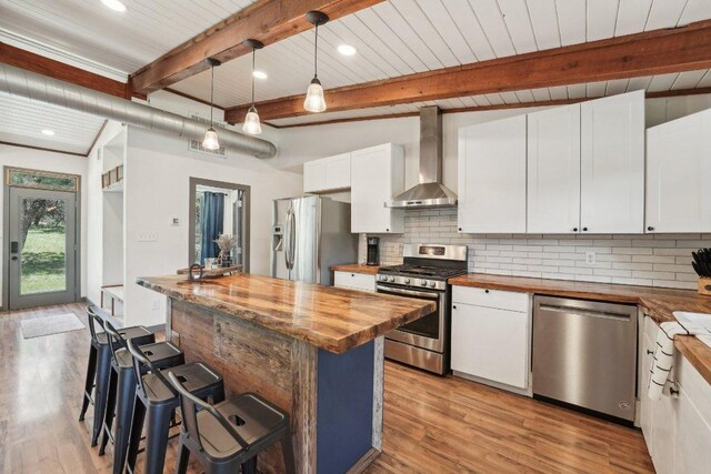 360 Little Barton Dr, Dripping Springs, TX 78620 - kitchen with wall chimney range hood, appliances with stainless steel finishes, butcher block countertops, tasteful backsplash, and white cabinetry