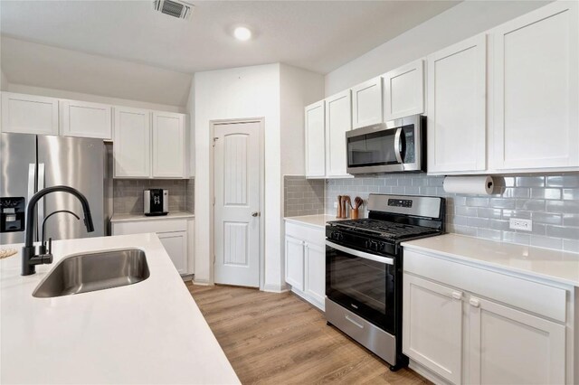 225 Sweetwater Creek Ln, Hutto, TX 78634 - kitchen featuring appliances with stainless steel finishes, a sink, light countertops, white cabinets, and backsplash