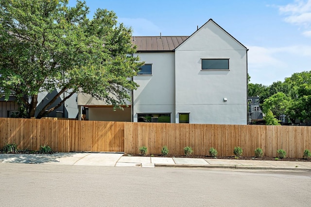 2403 E 22nd St, Austin, TX 78722 - view of side of home with a fenced front yard, stucco siding, a standing seam roof, and a metal roof