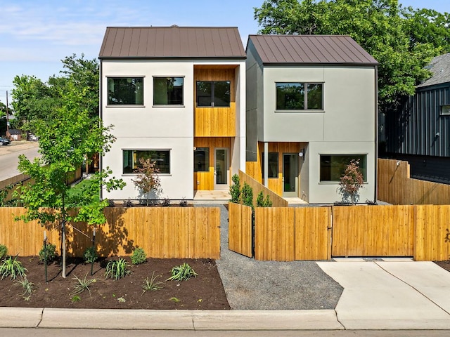 2403 E 22nd St, Austin, TX 78722 - contemporary home featuring a standing seam roof, stucco siding, a fenced front yard, and a gate