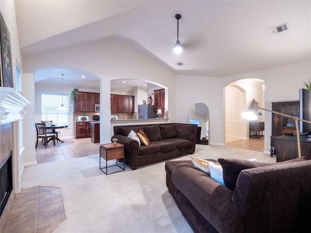 2214 Yellow Bird Trl, Austin, TX 78734 - living room with arched walkways, a fireplace, light carpet, lofted ceiling, and light tile patterned floors