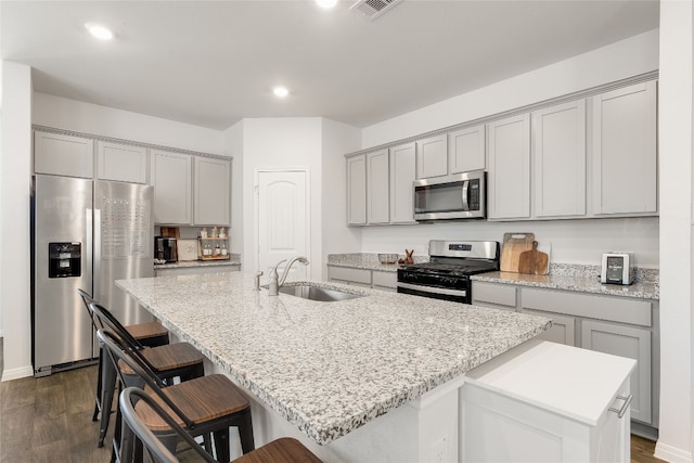 288 Caddo Bnd, Kyle, TX 78640 - kitchen featuring appliances with stainless steel finishes, gray cabinetry, an island with sink, a breakfast bar area, and recessed lighting