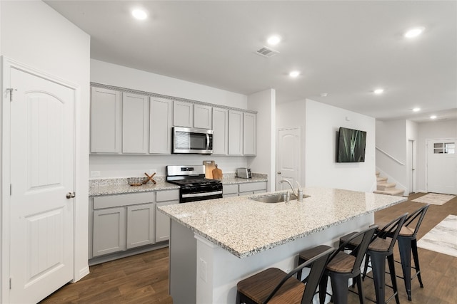 288 Caddo Bnd, Kyle, TX 78640 - kitchen featuring range with gas stovetop, stainless steel microwave, gray cabinets, recessed lighting, and a breakfast bar