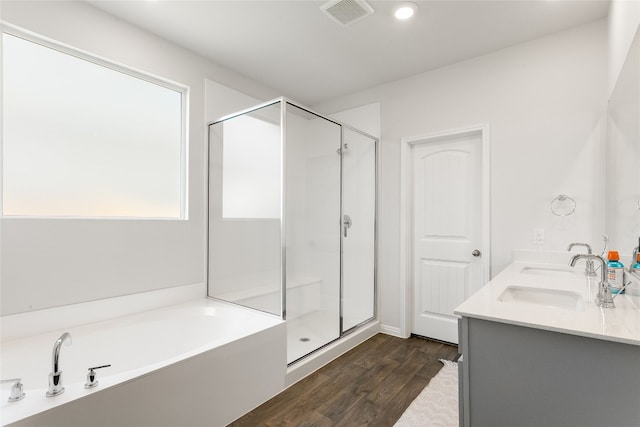 288 Caddo Bnd, Kyle, TX 78640 - bathroom with wood finished floors, a stall shower, a garden tub, double vanity, and recessed lighting
