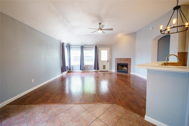 1118 Connemara Ln, Pflugerville, TX 78660 - unfurnished living room featuring a ceiling fan, a tile fireplace, light tile patterned floors, a chandelier, and vaulted ceiling