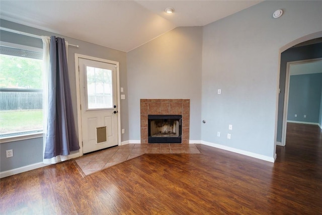 1118 Connemara Ln, Pflugerville, TX 78660 - unfurnished living room featuring wood finished floors, arched walkways, lofted ceiling, and a fireplace