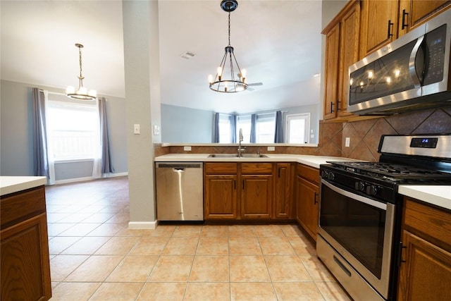 1118 Connemara Ln, Pflugerville, TX 78660 - kitchen featuring stainless steel appliances, a chandelier, a sink, brown cabinetry, and tasteful backsplash