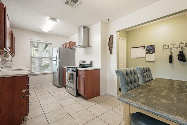 12320 Cedarspur Rd, Austin, TX 78758 - kitchen with wall chimney range hood, stainless steel appliances, light tile patterned floors, baseboards, and a textured ceiling