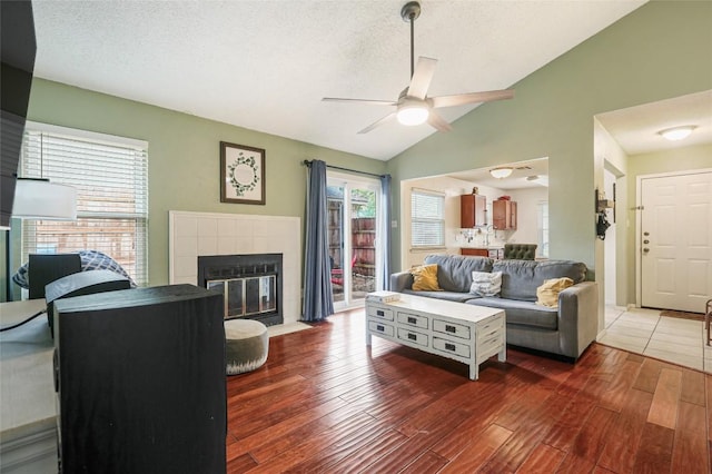 12320 Cedarspur Rd, Austin, TX 78758 - living room featuring ceiling fan, wood finished floors, a fireplace, lofted ceiling, and a textured ceiling