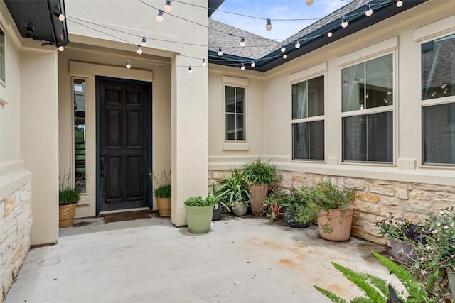 403 Baldovino Skwy, Austin, TX 78738 - entrance to property featuring stone siding, a patio area, roof with shingles, and stucco siding