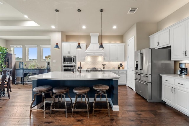 403 Baldovino Skwy, Austin, TX 78738 - kitchen with custom range hood, appliances with stainless steel finishes, a breakfast bar area, decorative backsplash, and dark wood finished floors