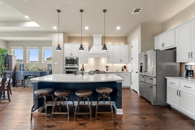 403 Baldovino Skwy, Austin, TX 78738 - kitchen with premium range hood, appliances with stainless steel finishes, a kitchen breakfast bar, decorative backsplash, and dark wood-style flooring