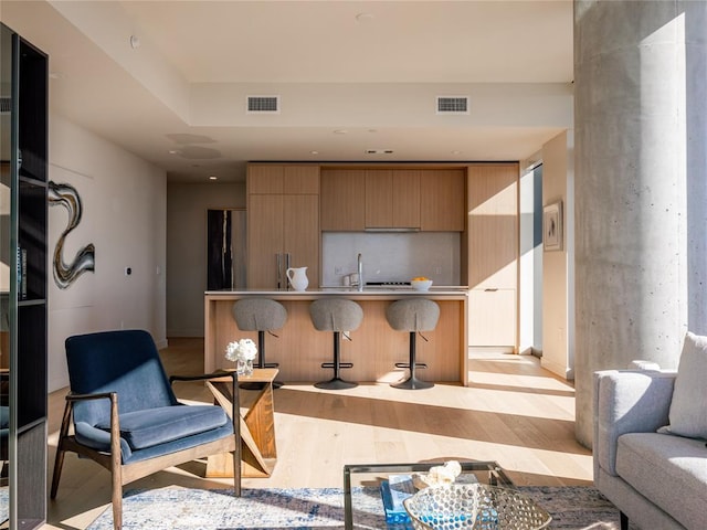 44 E Ave Unit 2910, Austin, TX 78701 - kitchen with light wood-style flooring, a kitchen breakfast bar, modern cabinets, a sink, and open floor plan