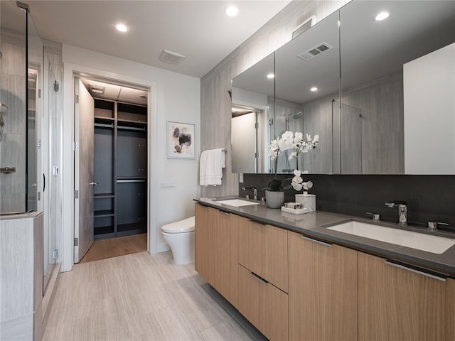 44 E Ave Unit 2910, Austin, TX 78701 - bathroom featuring a stall shower, double vanity, toilet, recessed lighting, and a walk in closet