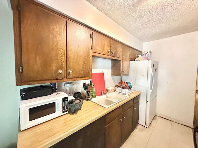 5005 S Pleasant Valley Rd, Austin, TX 78744 - kitchen featuring a sink, white appliances, light countertops, a textured ceiling, and light tile patterned floors