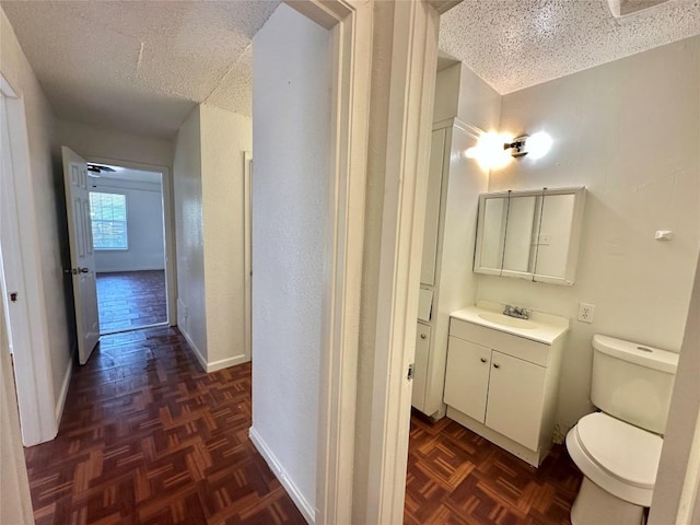 5005 S Pleasant Valley Rd, Austin, TX 78744 - bathroom with a textured ceiling, toilet, vanity, and baseboards