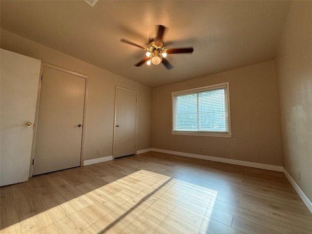 429 Camelback Rd, La Grange, TX 78945 - unfurnished bedroom with wood finished floors, two closets, baseboards, and a ceiling fan
