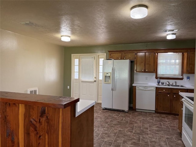 429 Camelback Rd, La Grange, TX 78945 - kitchen with white appliances, a sink, plenty of natural light, a textured ceiling, and brown cabinets