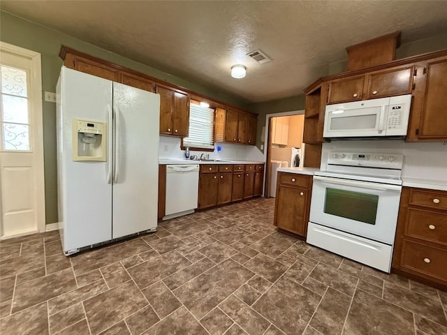 429 Camelback Rd, La Grange, TX 78945 - kitchen featuring white appliances, light countertops, brown cabinetry, and a textured ceiling