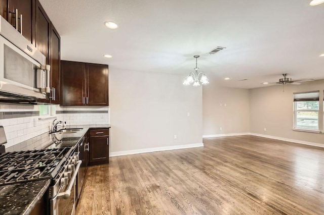 704 Wren Ave, Austin, TX 78753 - kitchen with stainless steel appliances, backsplash, dark brown cabinets, a chandelier, and recessed lighting