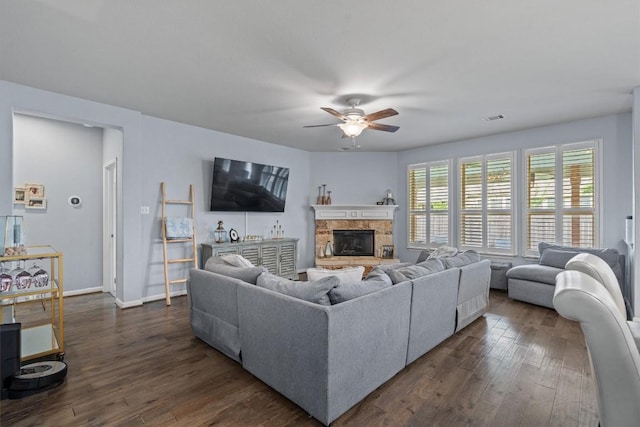 13625 Glen Creek Ct, Manor, TX 78653 - living room with ceiling fan, dark wood-style flooring, a stone fireplace, and baseboards