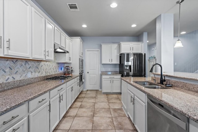 13625 Glen Creek Ct, Manor, TX 78653 - kitchen with appliances with stainless steel finishes, a sink, white cabinetry, under cabinet range hood, and light stone counters