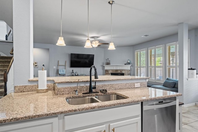 13625 Glen Creek Ct, Manor, TX 78653 - kitchen featuring stainless steel dishwasher, a sink, open floor plan, light stone countertops, and white cabinetry