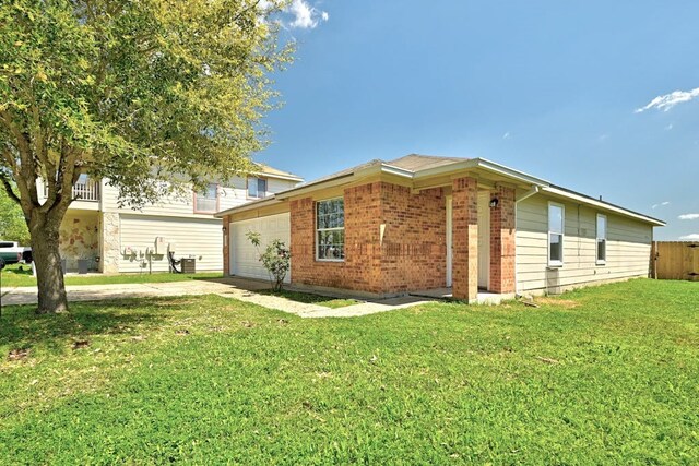 6317 Vida Nueva Ave, Del Valle, TX 78617 - view of side of home with a garage, brick siding, a yard, and driveway