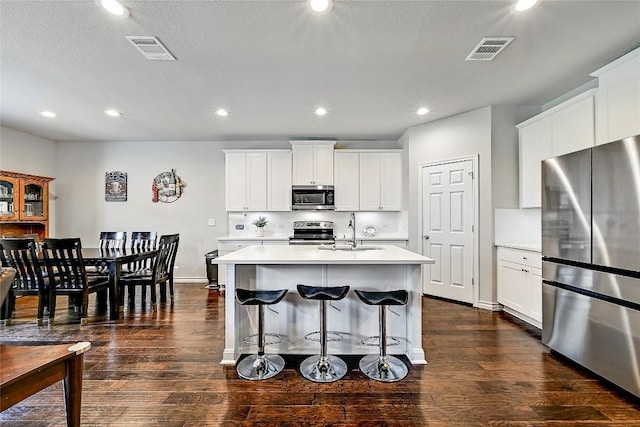 1304 Eagle Ridge Trl, Leander, TX 78641 - kitchen featuring appliances with stainless steel finishes, light countertops, a center island with sink, a kitchen bar, and recessed lighting
