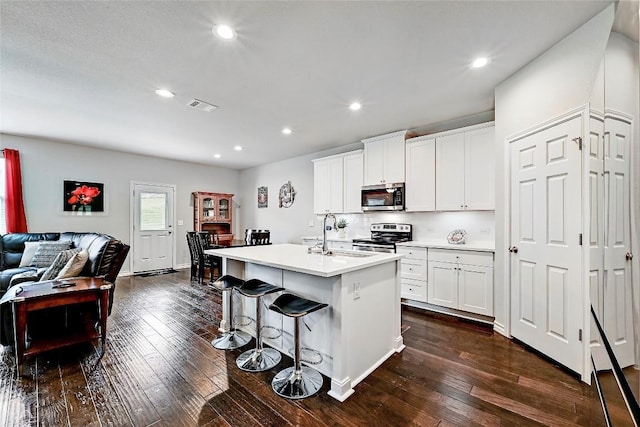 1304 Eagle Ridge Trl, Leander, TX 78641 - kitchen with stainless steel appliances, open floor plan, dark wood-style floors, a center island with sink, and recessed lighting