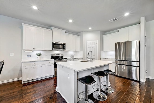 1304 Eagle Ridge Trl, Leander, TX 78641 - kitchen featuring appliances with stainless steel finishes, dark wood-type flooring, an island with sink, recessed lighting, and white cabinetry