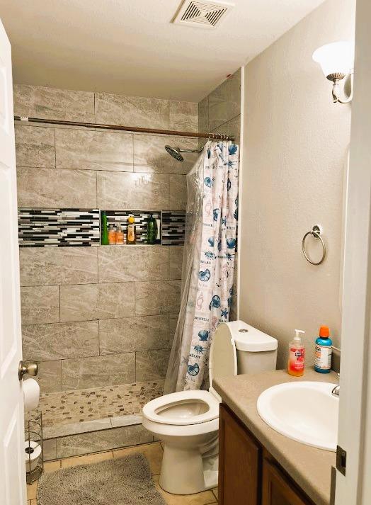 5105 Bantom Woods Bnd, Austin, TX 78724 - bathroom featuring toilet, a stall shower, vanity, and tile patterned floors
