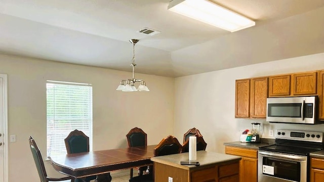 5105 Bantom Woods Bnd, Austin, TX 78724 - kitchen with appliances with stainless steel finishes, brown cabinetry, a chandelier, hanging light fixtures, and dark countertops