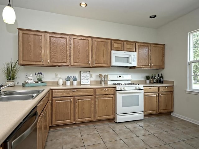 708 Texas Dr, Georgetown, TX 78633 - kitchen featuring white appliances, a sink, light tile patterned floors, light countertops, and brown cabinetry