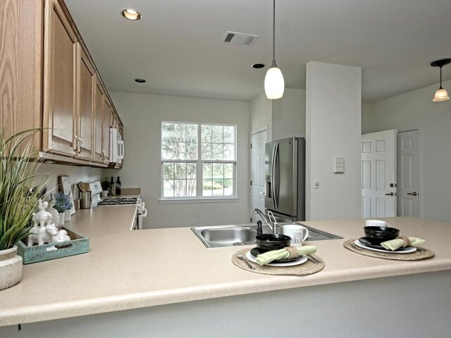708 Texas Dr, Georgetown, TX 78633 - kitchen with white appliances, light countertops, brown cabinetry, decorative light fixtures, and a sink