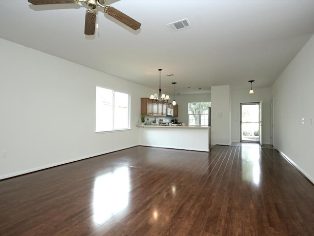 708 Texas Dr, Georgetown, TX 78633 - unfurnished living room with a chandelier, dark wood-style floors, ceiling fan, and baseboards