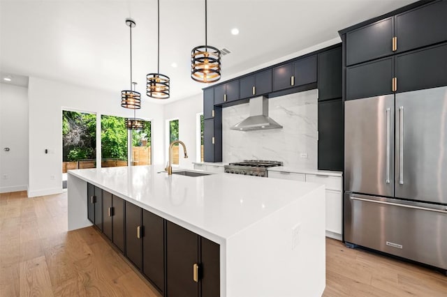 1305 Walnut Ave, Austin, TX 78702 - kitchen featuring high end refrigerator, wall chimney exhaust hood, a sink, light wood-type flooring, and recessed lighting