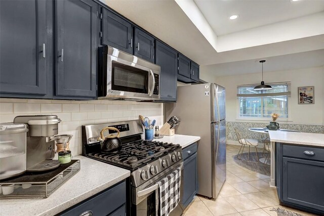 2714 Inridge Dr, Austin, TX 78745 - kitchen featuring appliances with stainless steel finishes, light countertops, light tile patterned floors, hanging light fixtures, and decorative backsplash