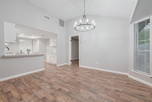 7614 Andiron Cir, Houston, TX 77041 - unfurnished living room featuring a sink, a chandelier, high vaulted ceiling, light wood-style flooring, and baseboards