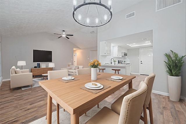 7614 Andiron Cir, Houston, TX 77041 - dining area featuring light wood finished floors, a chandelier, baseboards, lofted ceiling, and a ceiling fan