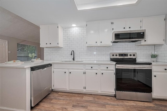 7614 Andiron Cir, Houston, TX 77041 - kitchen with appliances with stainless steel finishes, a sink, white cabinetry, a peninsula, and tasteful backsplash