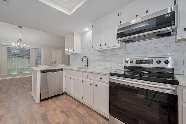 7614 Andiron Cir, Houston, TX 77041 - kitchen with stainless steel appliances, a sink, a chandelier, and white cabinetry