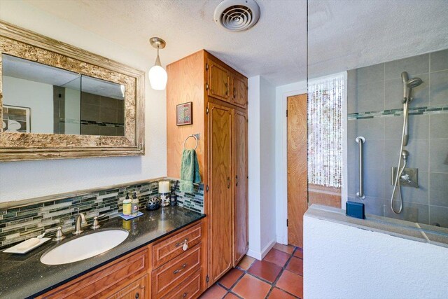 full bath with a tile shower, vanity, decorative backsplash, tile patterned floors, and a textured ceiling