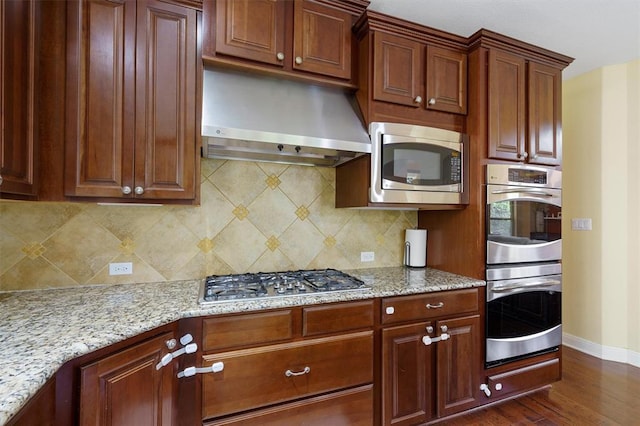 3904 Avery Woods Ln, Cedar Park, TX 78613 - kitchen with appliances with stainless steel finishes, wall chimney range hood, baseboards, dark wood-style floors, and light stone counters