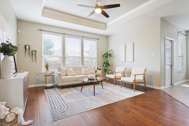 3408 Glastonbury Trl, Pflugerville, TX 78660 - living room featuring a tray ceiling, a ceiling fan, wood finished floors, crown molding, and baseboards