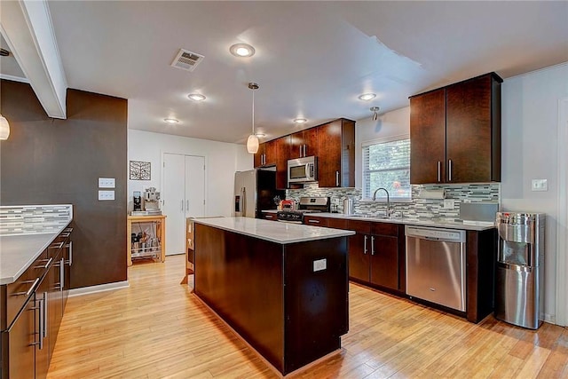 1706 Ridgemont Dr, Austin, TX 78723 - kitchen with appliances with stainless steel finishes, a sink, light wood-style flooring, backsplash, and a center island