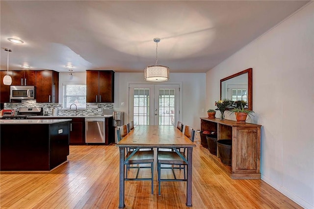 1706 Ridgemont Dr, Austin, TX 78723 - kitchen featuring appliances with stainless steel finishes, light wood-type flooring, tasteful backsplash, pendant lighting, and french doors